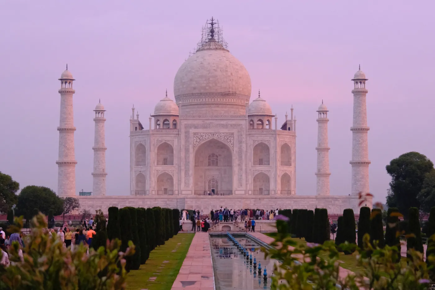 The Taj Mahal at dusk with visitors along the reflecting pool