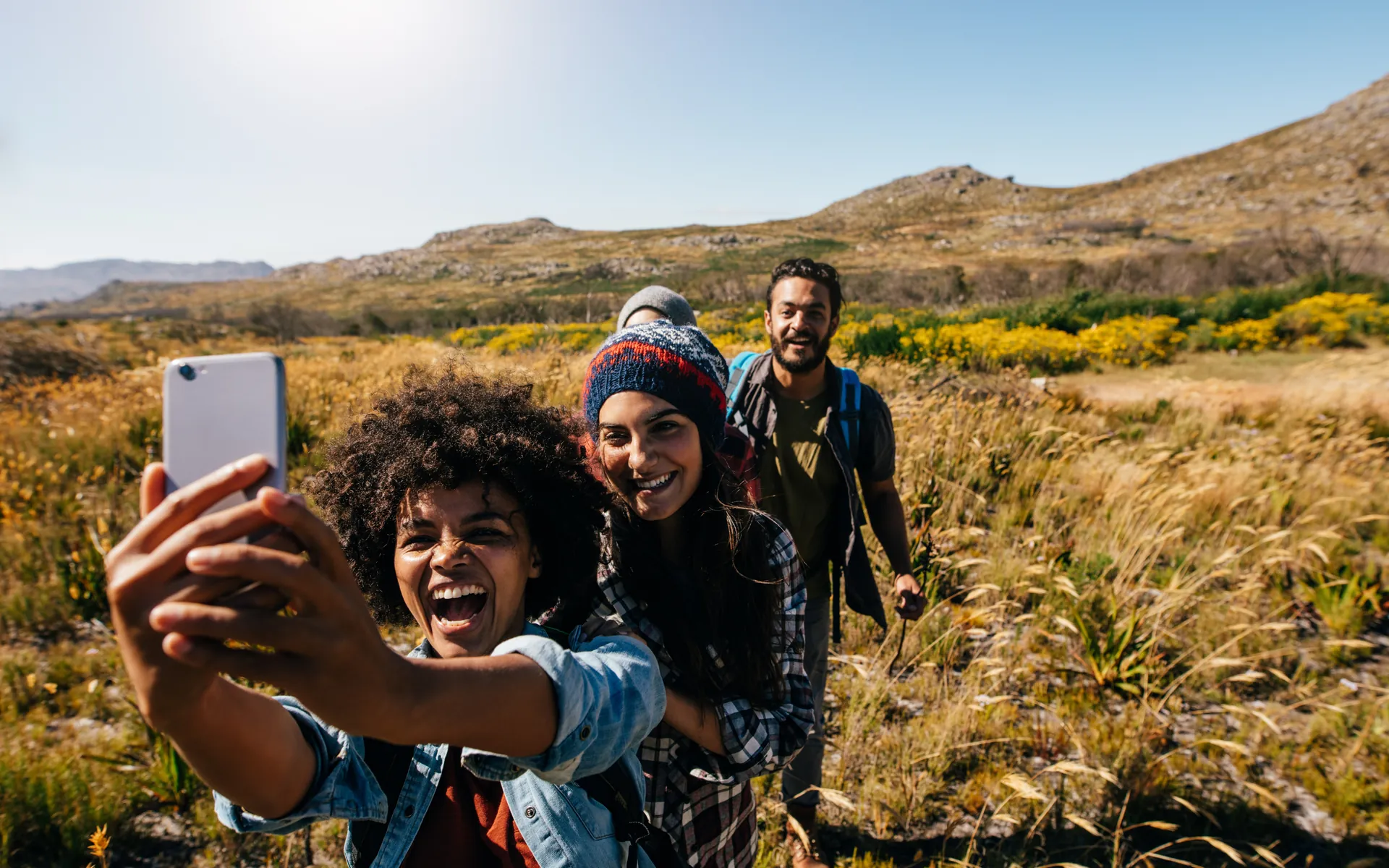 Friends taking a hiking selfie in golden hillside grass